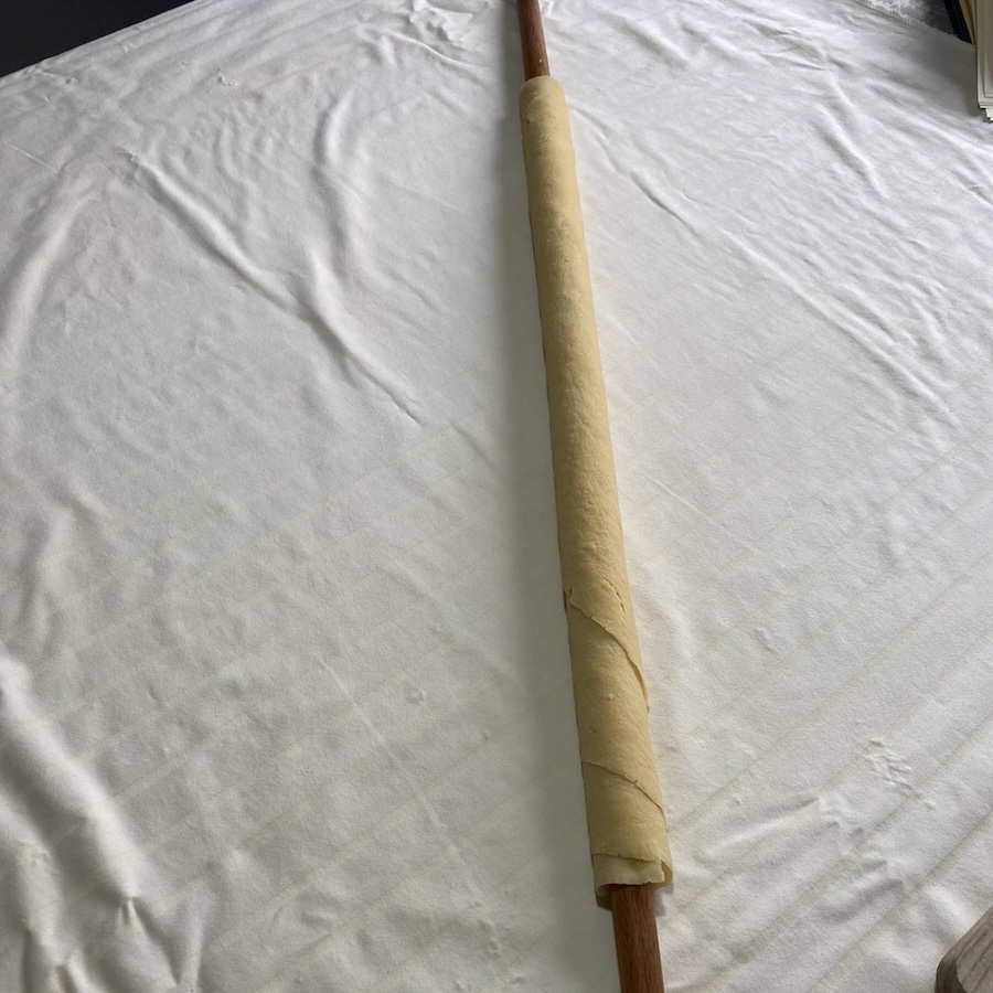 Thin yufka fo bosnian pilav on a long rolling pin